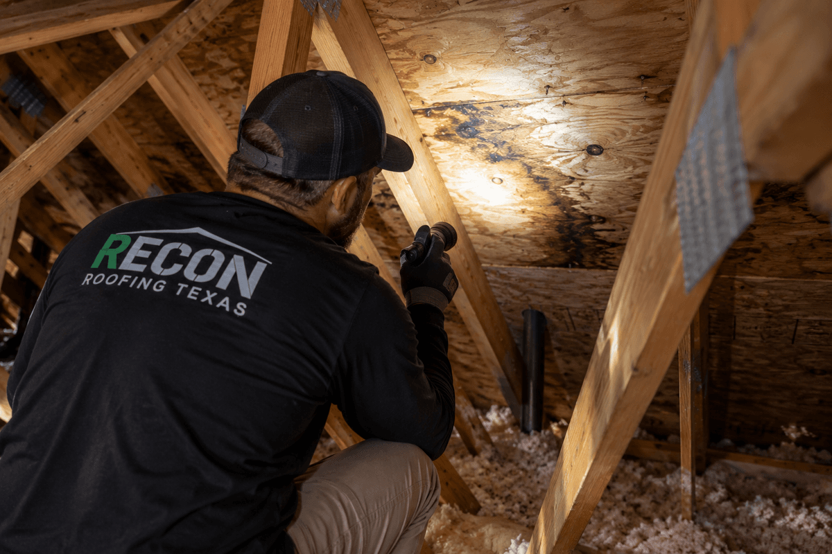 Recon Roofing technician checking the underside of a roof deck for attic ventilation problems